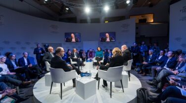 A group of people engaged in strategic innovation, sitting around a table in a global room.