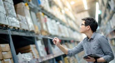 A strategic consultant in a warehouse holding a tablet.