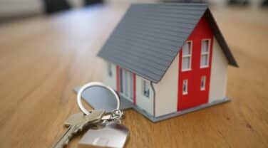 A tech model of a house with keys on a table.