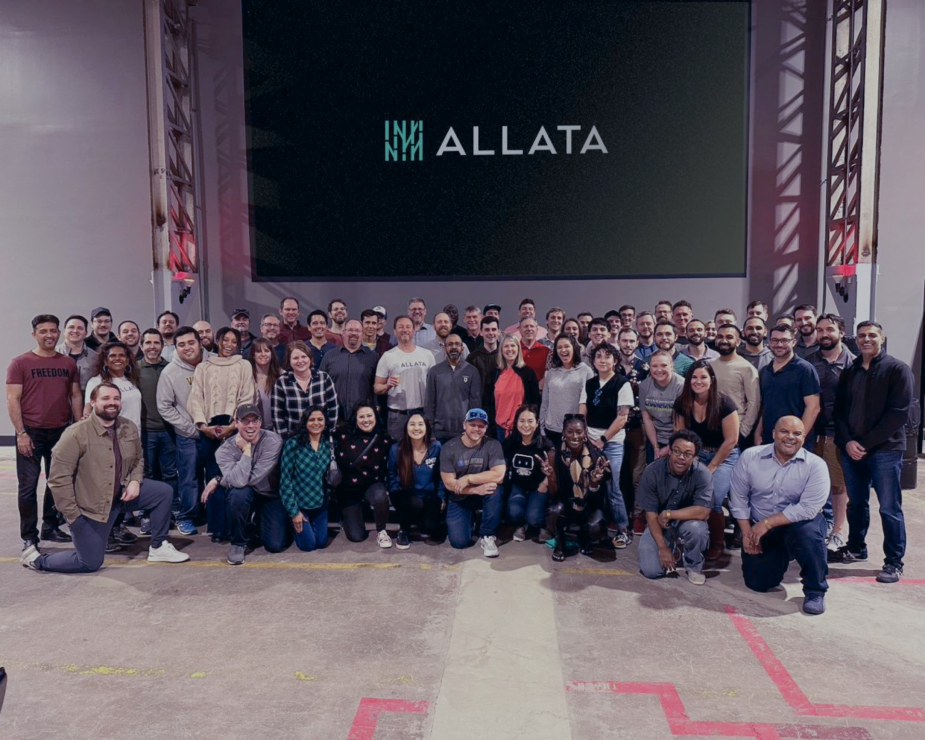 A group of people posing for a picture in front of a large screen at a corporate event.